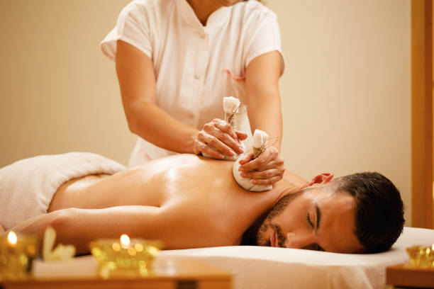istock Young man getting back massage with herbal balls at health spa. 1182968700