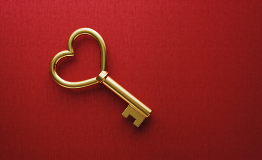 Gold heart shaped key on red background. Horizontal composition with copy space.