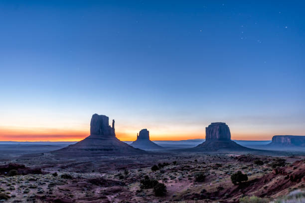 berühmte aussicht im monument valley von buttes und horizont während der blauen morgendämmerung nacht mit sonnenaufgang buntes licht in arizona mit himmel und silhouette - merrick butte stock-fotos und bilder