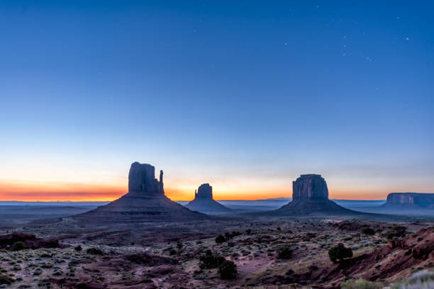 famous view in monument valley of buttes and horizon during blue dawn night with sunrise colorful light in arizona with sky and silhouette - merrick butte imagens e fotografias de stock