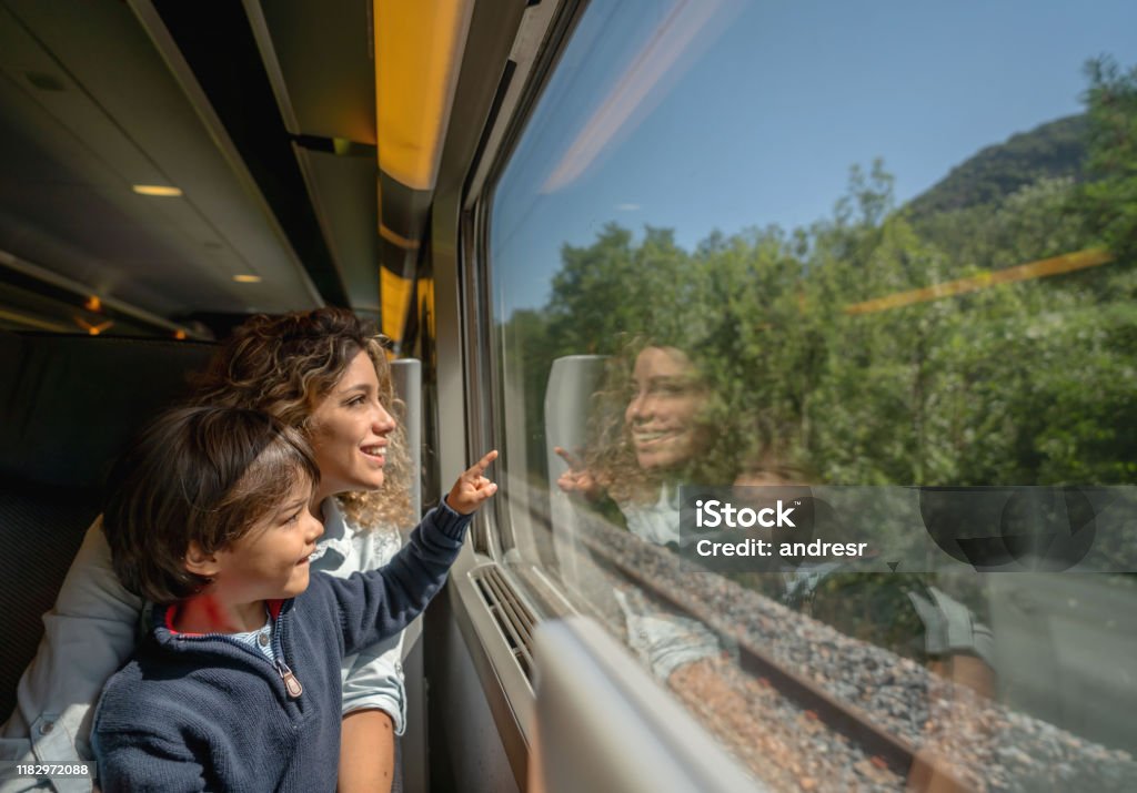 Mother and son riding on the train and looking through the window Portrait of a happy mother and son riding on the train and looking through the window while pointing away - transport concepts Train - Vehicle Stock Photo