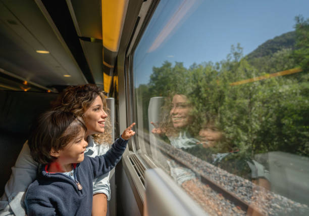 Mother and son riding on the train and looking through the window Portrait of a happy mother and son riding on the train and looking through the window while pointing away - transport concepts riding stock pictures, royalty-free photos & images
