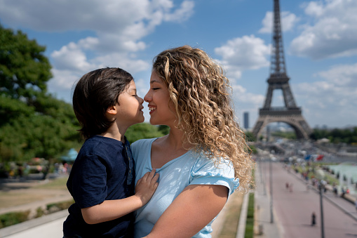 Loving portrait of a mother and son in Paris with the Eiffel Tower at the background and looking very happyÂ