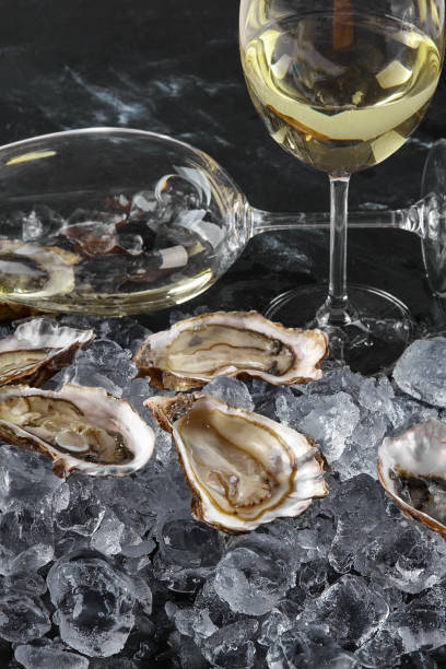 oysters in a plate with ice and lemon, in the hands of the chef and a glass of dry white wine, on a wooden background. Seafood, restaurant, delicious taste