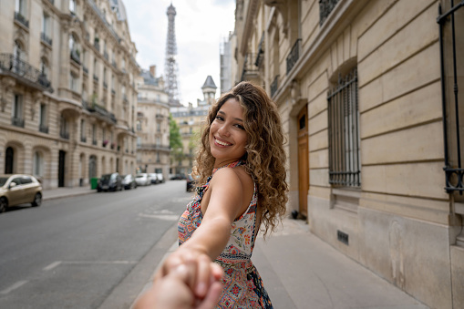 Portrait of a happy woman in Paris holding hands with her partner - follow me concepts
