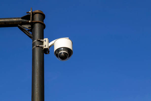 istock White street camera of external supervision installed on an outdoors pole against a blue sky. Modern CCTV camera, surveillance and monitoring. 1182977985