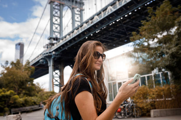 istock Woman using phone with Manhattan Bridge in background 1182980352