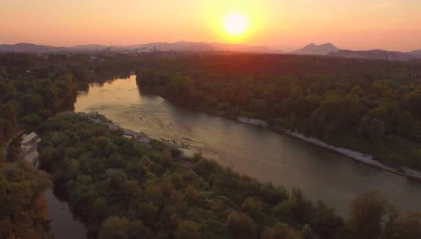 istock AERIAL: Flying over a calm river running through the green forest at sunset. 1182981924