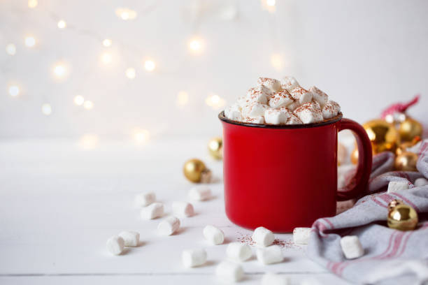 Cup of hot cocoa or chocolate with marshmallow on white background. Spring and winter concept. Close up. Red cup of hot chocolate with marshmallow on christmas lights background and christmas decor. Cozy winter concept. New Year atmosphere. Copy space. hot chocolate stock pictures, royalty-free photos & images