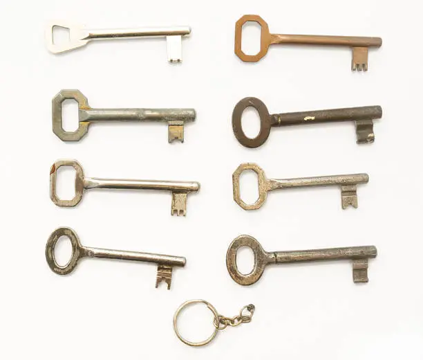 Eight old skeleton keys and a key holder isolated on white