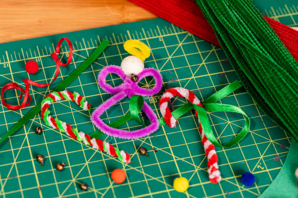 holiday pipe cleaner crafts. a tight framed angel and candy canes made of pipe cleaners, with additional supplies scattered around the finished crafts on a green cutting mat.  there are scattered negative spaces for bullet text copy. - scrapbooking office supply art and craft equipment scissors imagens e fotografias de stock