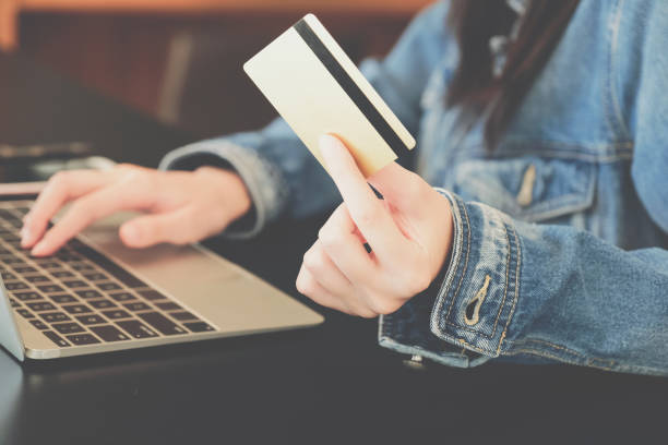 istock woman holding credit card using computer for shopping online 1182994954