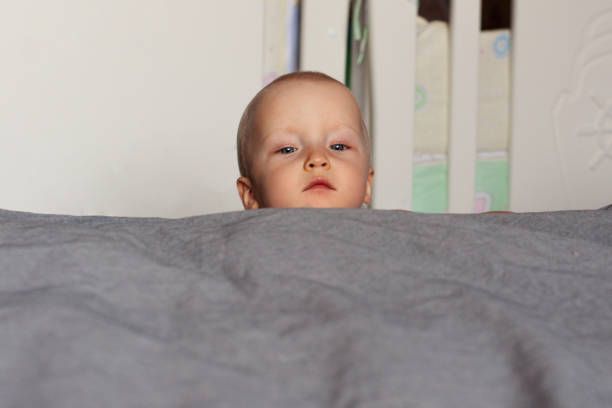 istock Curiosity. A curious baby's face peeks out over the bed. Education, interest, emotions. Face close up. 1182995206