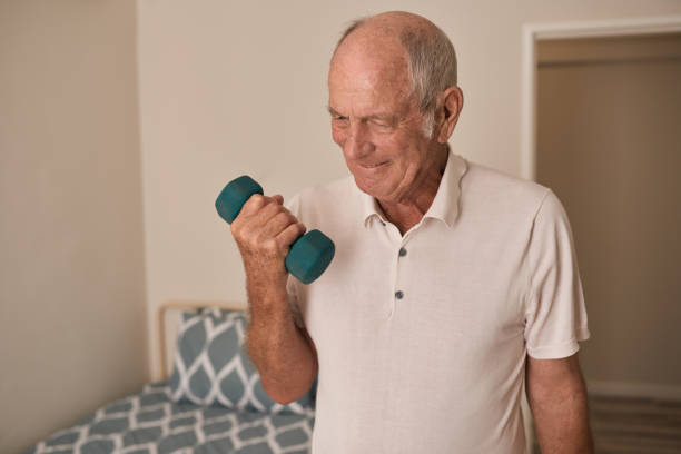 Smiling senior man lifting weights in his retirement home room