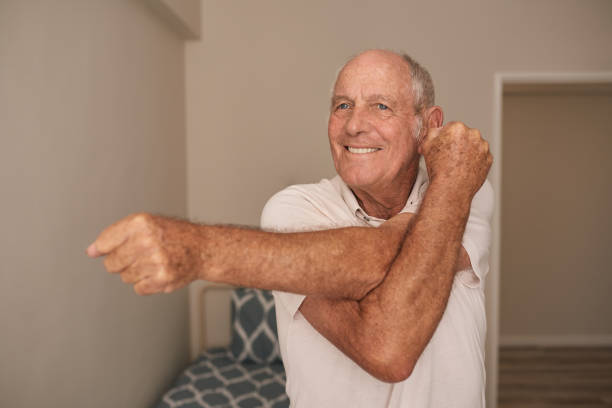 istock Smiling senior man doing stretches in his retirement home room 1183002999