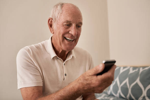 istock Smiling senior man sitting on his bed using a cellphone 1183003146