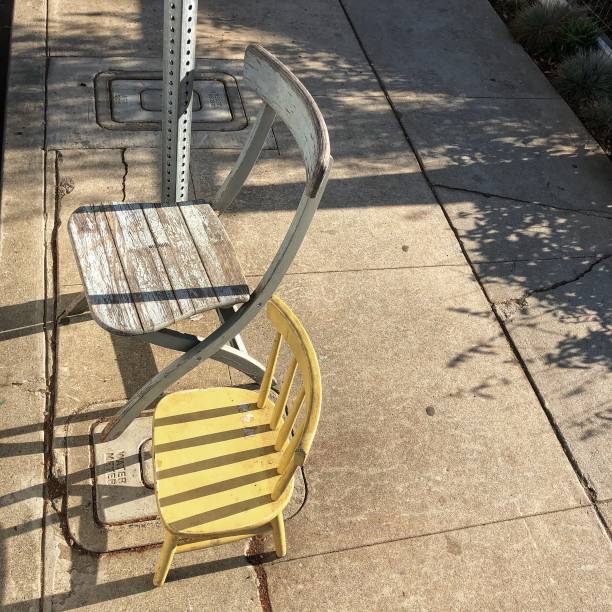 istock Two wooden chairs abandoned on city sidewalk 1183003243