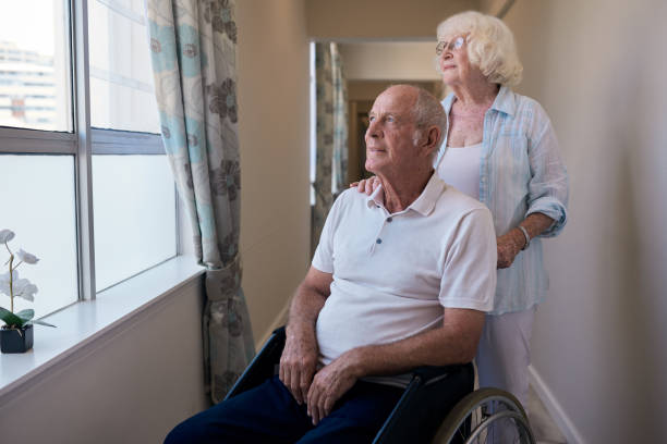 istock Smiling senior man looking through a window with his wife 1183005857
