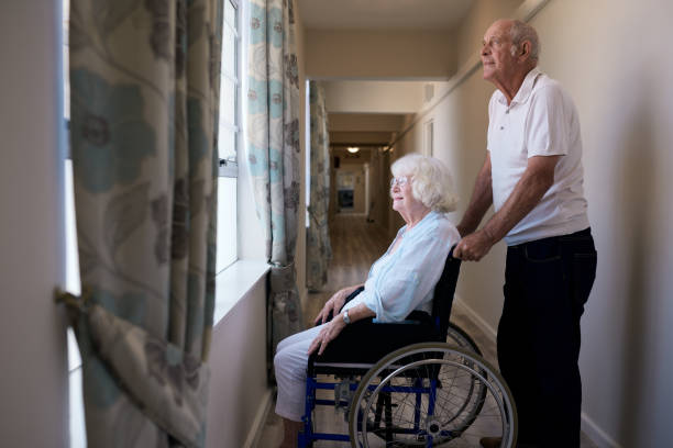 istock Smiling senior woman looking through a window with her husband 1183006113