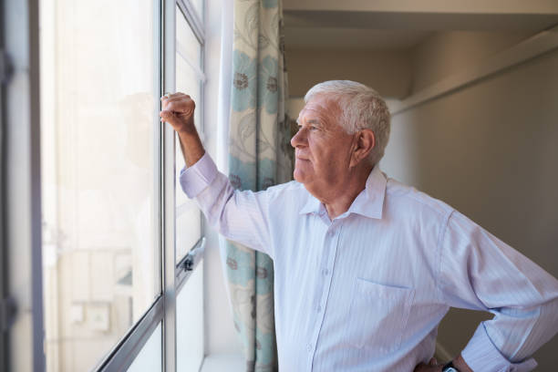 istock Senior man looking through a retirement home window 1183006849