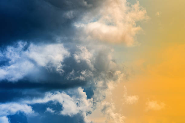 Dramatic blue thunderclouds on left, stunning yellow-golden fluffy clouds illuminated by rays of sun on right. Amazing view natural meteorology background, cloud scape to change weather before rain.