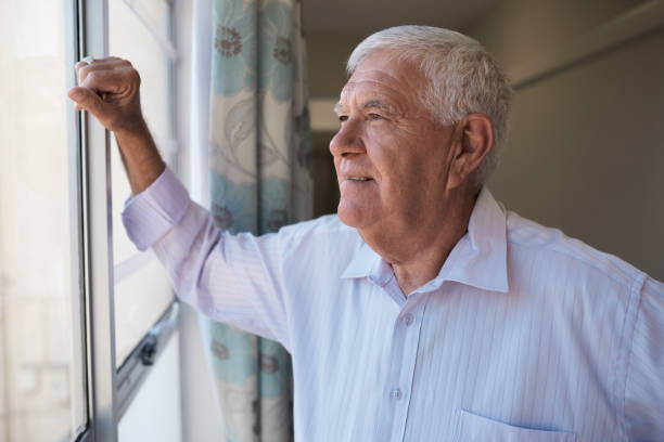 istock Senior man smiling while looking through a retirement home window 1183006945