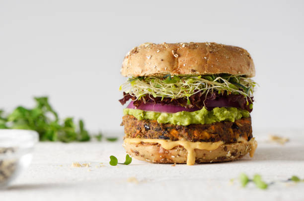 Healthy veggie burger Healthy veggie burger with vegan pattie, guacamole, onion and sprout veganism photos stock pictures, royalty-free photos & images