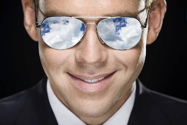Close-up of a male pilot wearing glasses reflecting the sky stock photo