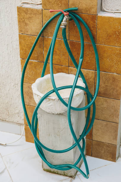 istock Old wall tap with a coiled green hosepipe 1183024496