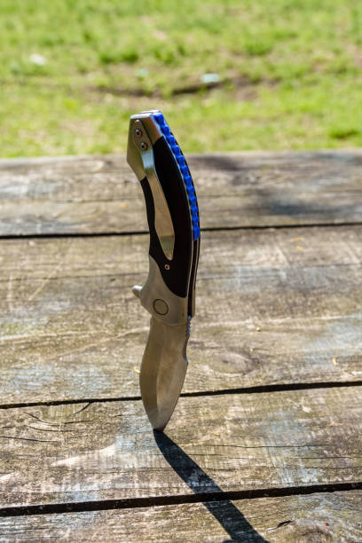 istock Folding knife stuck in the old wooden board 1183024509