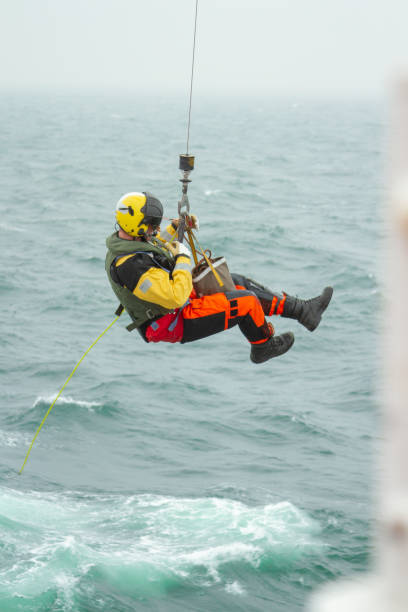 at sea - english channel - oct 1st 2012: coast guard search and rescue helicopter sar training, hoisting a person at sea - rescue helicopter water searching imagens e fotografias de stock