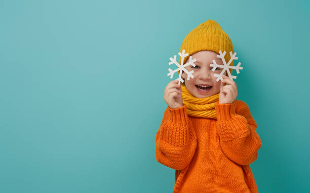 Winter portrait of happy child Winter portrait of happy child wearing knitted hat, snood and sweater. Girl having fun, playing and laughing on teal background. Fashion concept. children in winter stock pictures, royalty-free photos & images