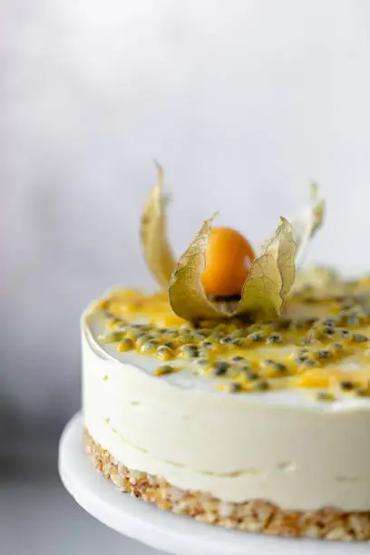 Passionfruit vegan cheesecake with Physalis on marble background with copy space