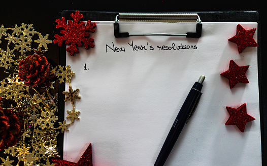 Writing New Year`s Resolutions for Christmas. Christmas Resolutions. Text New Year`s Resolutions on paper.