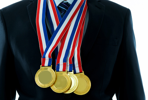 Hand hold Gold medal on yellow blue ribbon isolated on yellow background. Medal mockup.