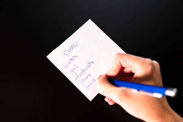 istock Writing on sticky note list of costs. Text with costs on paper. 1183039140