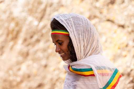 Orthodox Christian ethiopian bashful woman in front of famous rock-hewn St. George's Church after Mass on May 1st. 2019 in Lalibela, Ethiopia