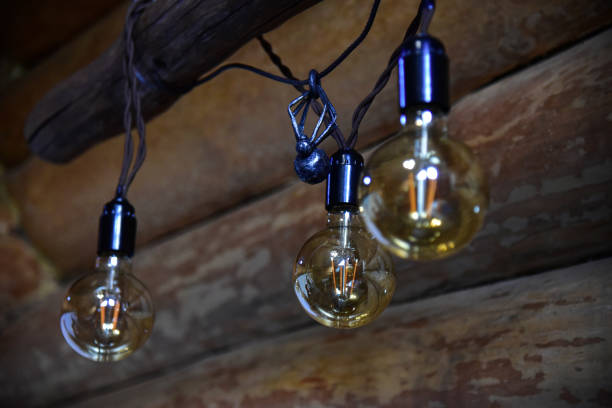 istock Retro style light bulbs hanging in a wooden room 1183047077