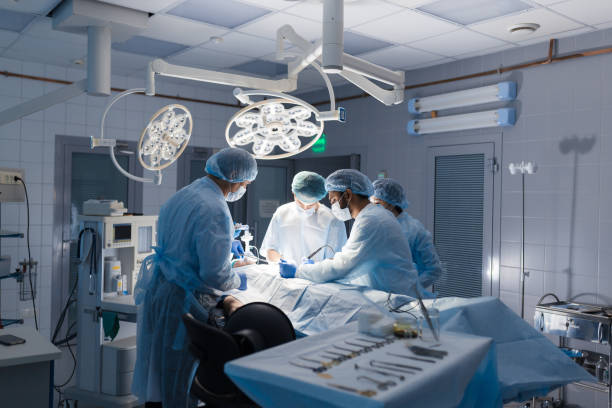 Team of Surgeons Operating in the Hospital Multiracial Team of Surgeons concentrating on a patient during a heart surgery at a hospital. Mature caucasian doctor sharing his experiences with multiethnic colleagues. teatro stock pictures, royalty-free photos & images