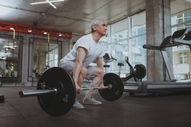 hombre mayor haciendo ejercicio en el gimnasio - peso muerto fotografías e imágenes de stock