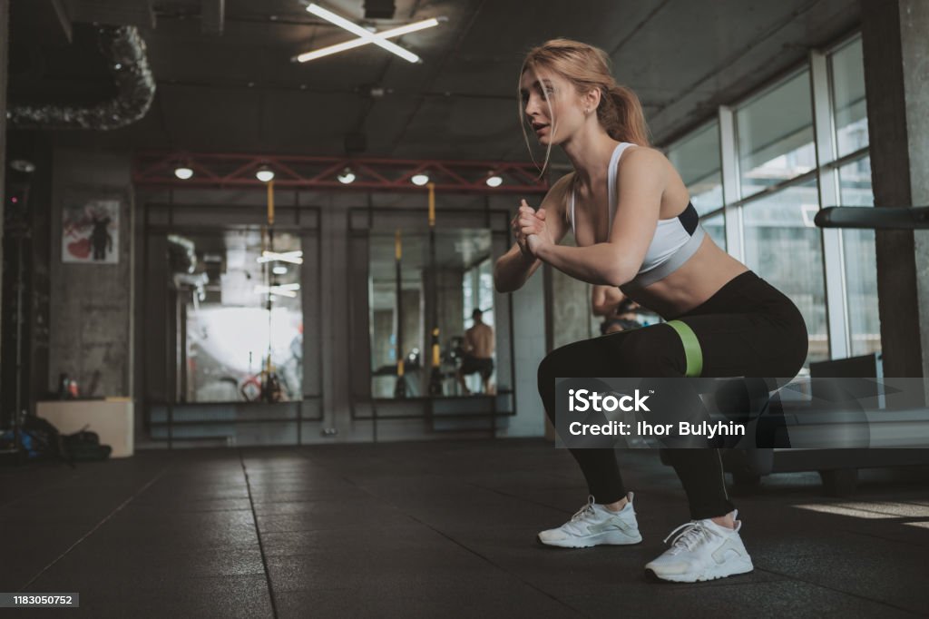 Schönejunge athletische Frau beim Training im Fitnessstudio - Lizenzfrei Hockend Stock-Foto