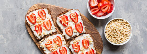 istock Healthy breakfast. Black bread with strawberry, pine nuts and cheese on gray concrete background. Authentic lifestyle image. Flat Lay, Copy space, top view, overhead, mockup, template. Food concept 1183051950