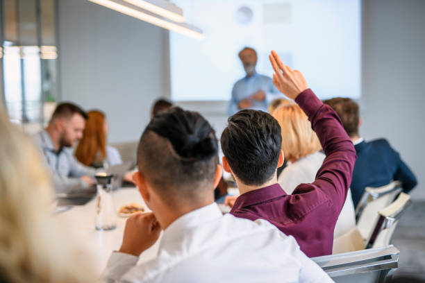 istock Young Businessman with Raised Hand in Meeting 1183053281
