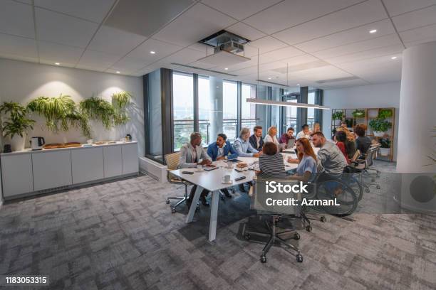 Executive Team Sitting At Conference Table In Board Room Stock Photo - Download Image Now