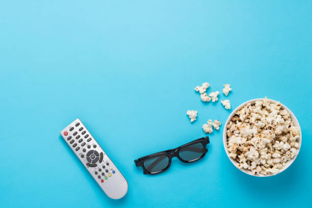 istock Bowl with popcorn, Imax glasses, remote control for TV on a blue 1183054923