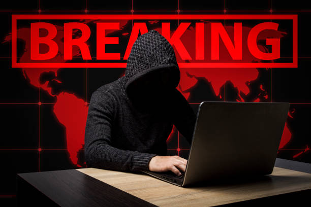 istock Faceless man in a hooded robe sits at a table with a laptop. Con 1183055070