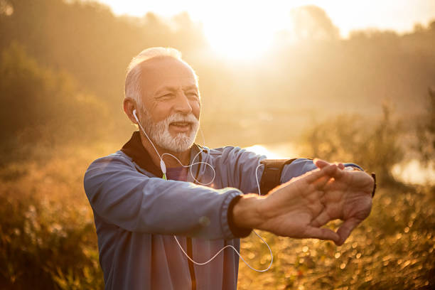 istock Senior jogger by lake in morning time stretching hands 1183055331