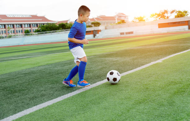 istock Young boy playing soccer ball on the field 1183055495
