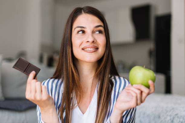 mujer eligiendo entre chocolate y manzana - apple women green eating fotografías e imágenes de stock