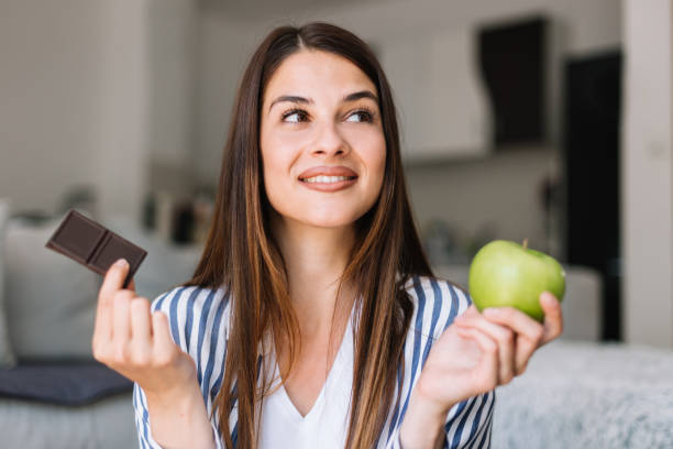 женщина, выбирающих между шоколадом и яблоком - apple women green eating стоковые фото и изображения